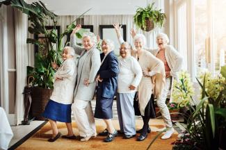 Elderly women dancing in line, waving, laughing, and having fun